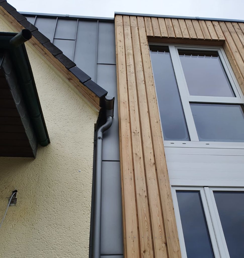 Zu sehen ist eine komplett neu erstellte Fassade an einem Haus. Holz und Metallverkleidung professionell eingesetzt durch Firstetage Leverkusen.